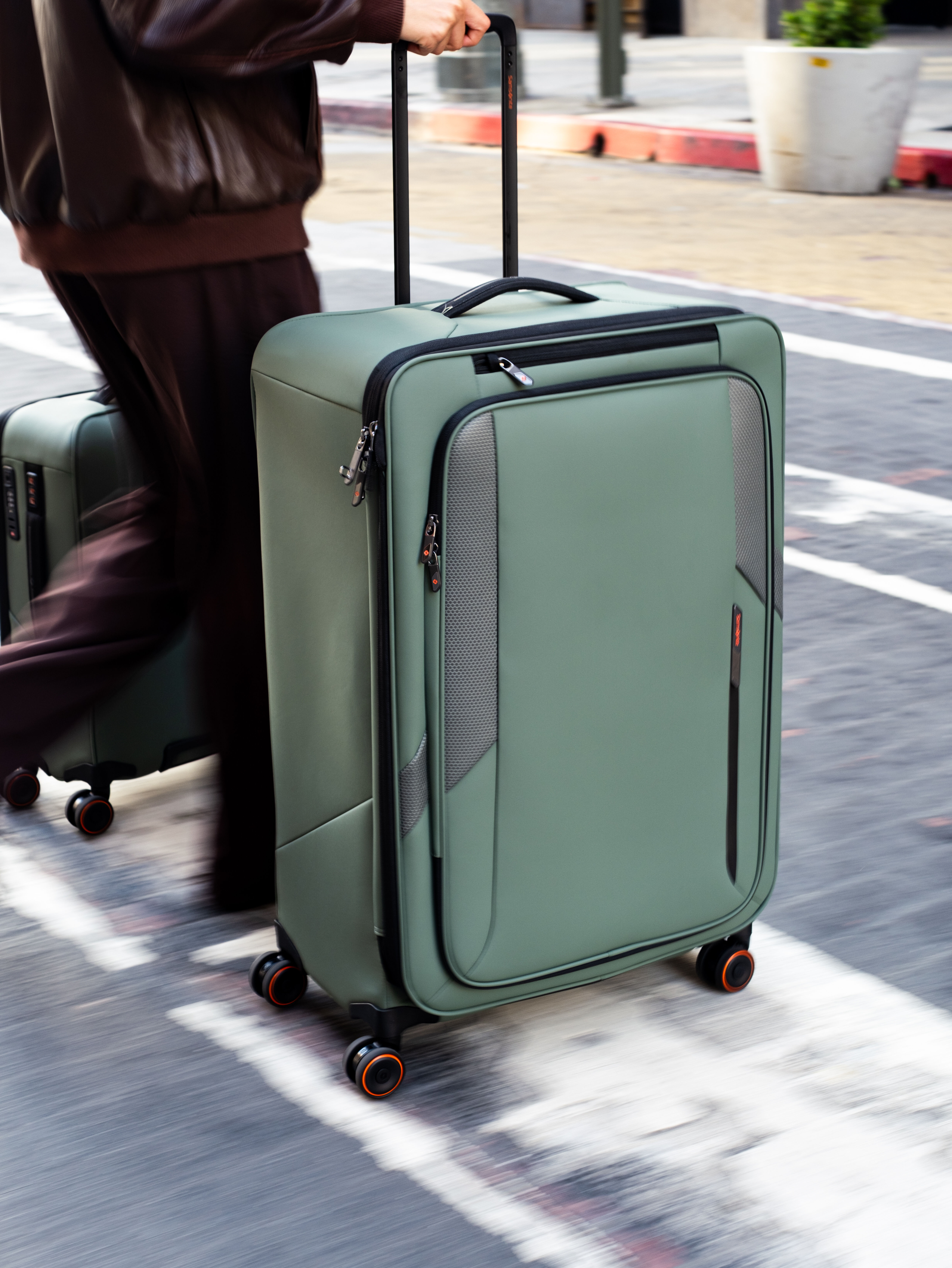 Lifestyle image: a person walking with Softside suitcases